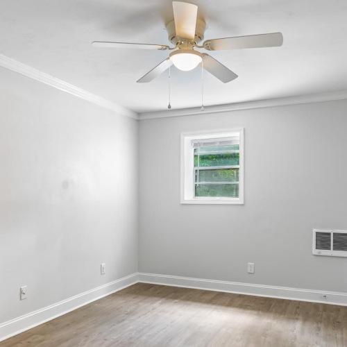 a room with a ceiling fan and a wood floor